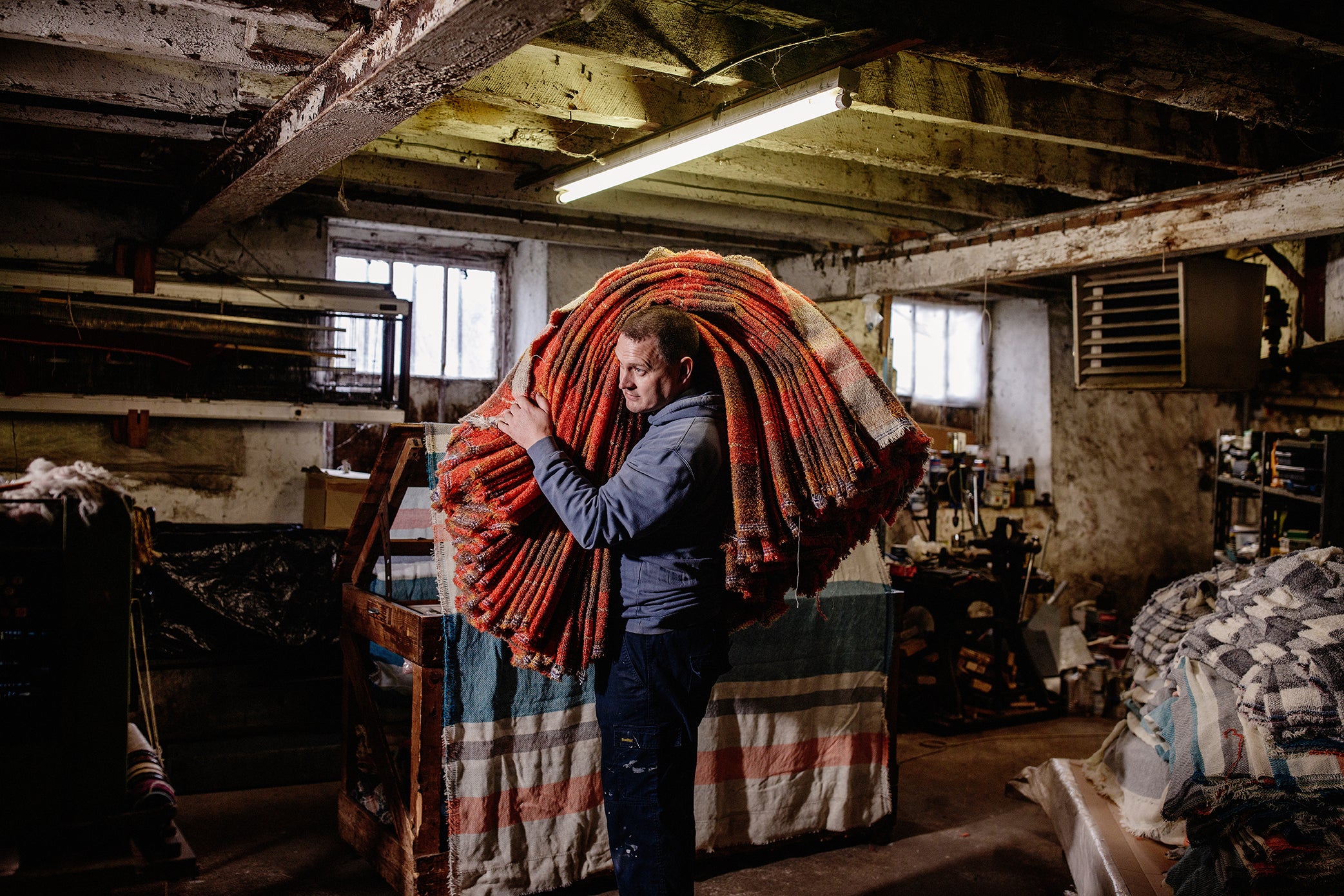 Portrait of Thomas hauling fabric over his shoulder at the mill