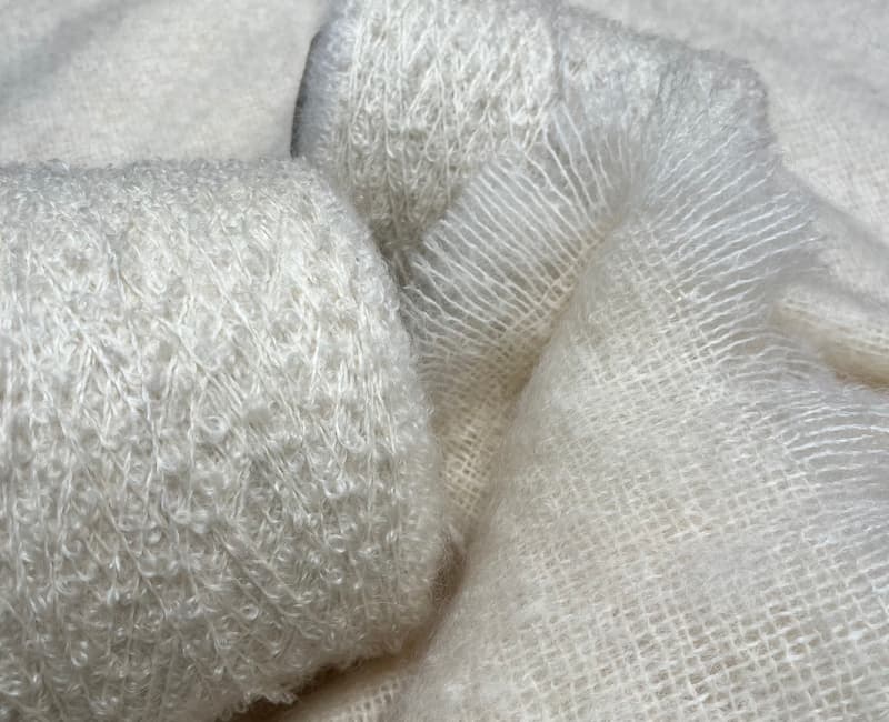 Close up shot of spools of white mohair wool, on a white mohair blanket