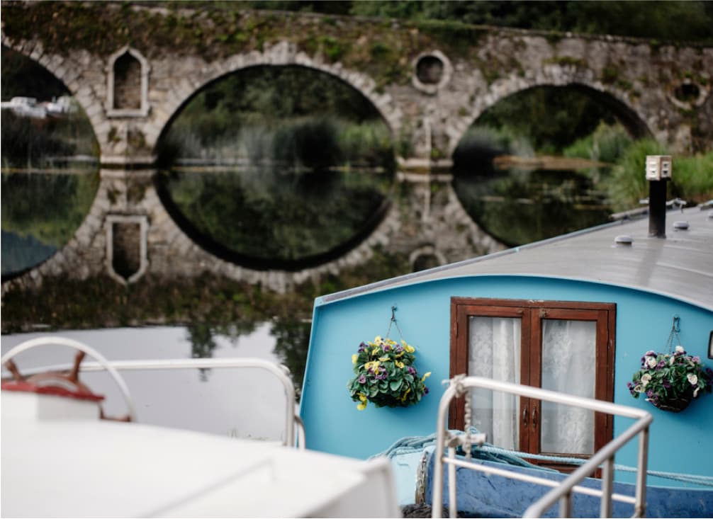 Shot taken on a light blue canal barge overlooking  a river with Graiguenamanagh bridge in the background 