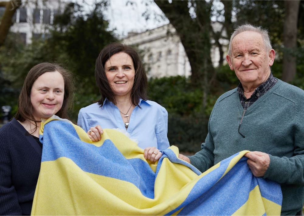 Miriam and Philip Cushen holding the Ukrainian blue and yellow striped blanket with Ellie Dunne