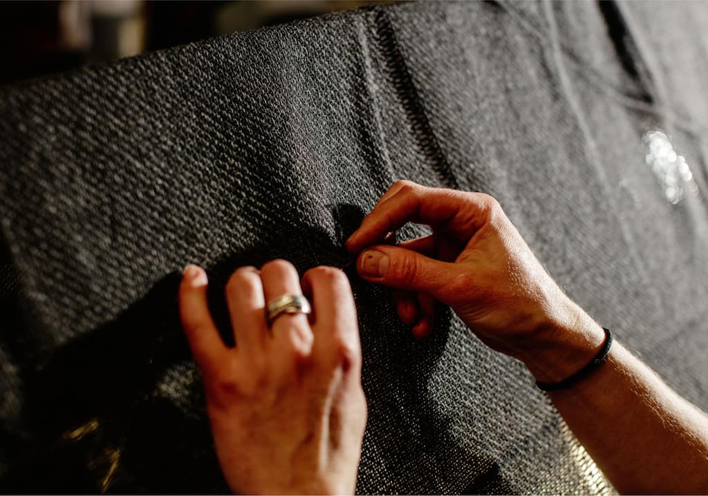Hands stitching and repairing a piece of fabric