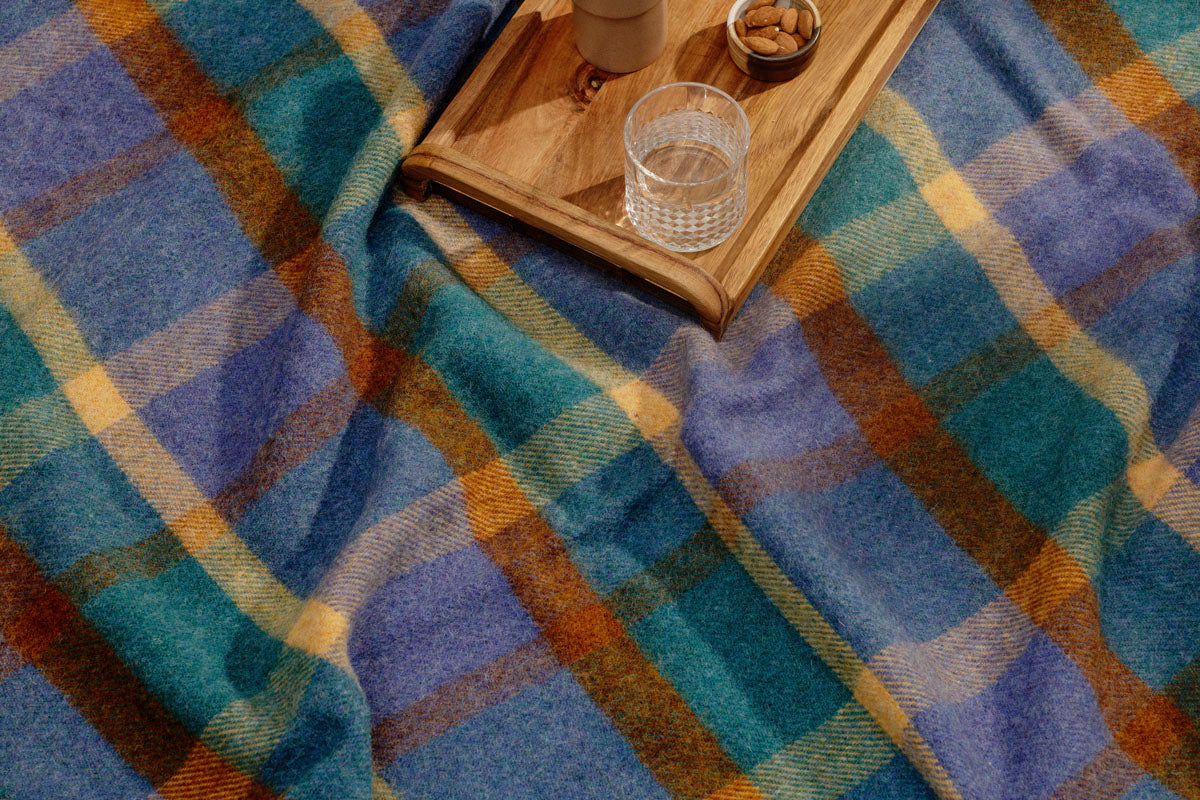 Multi-coloured plaid picnic blanket with a wooden food tray on top