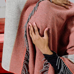 Dancer with red and grey woollen blanket over her head holds her head with her hand