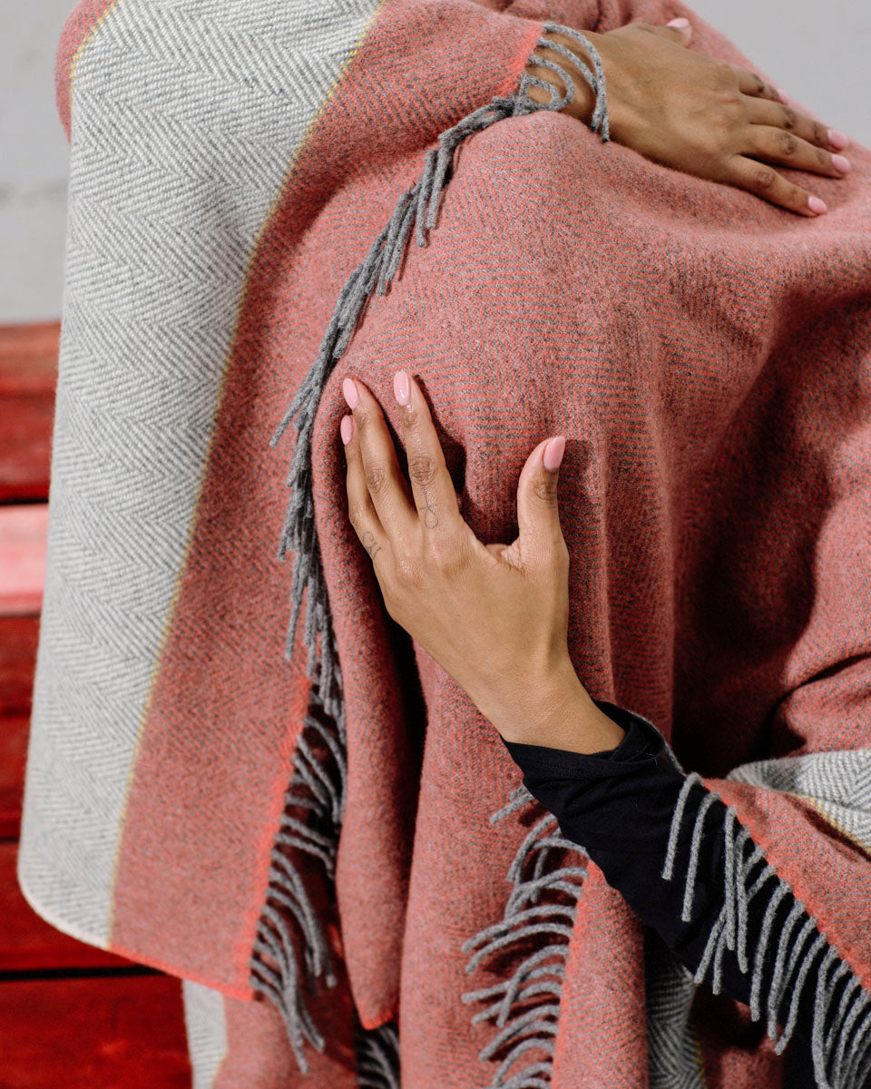 Dancer with red and grey woollen blanket over her head holds her head with her hand